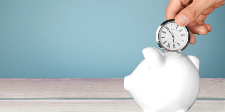 Hand putting clock in piggy bank