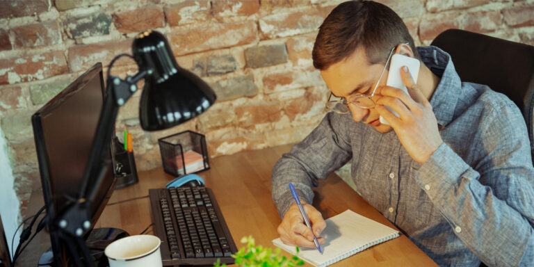 Man on phone next to computer screen